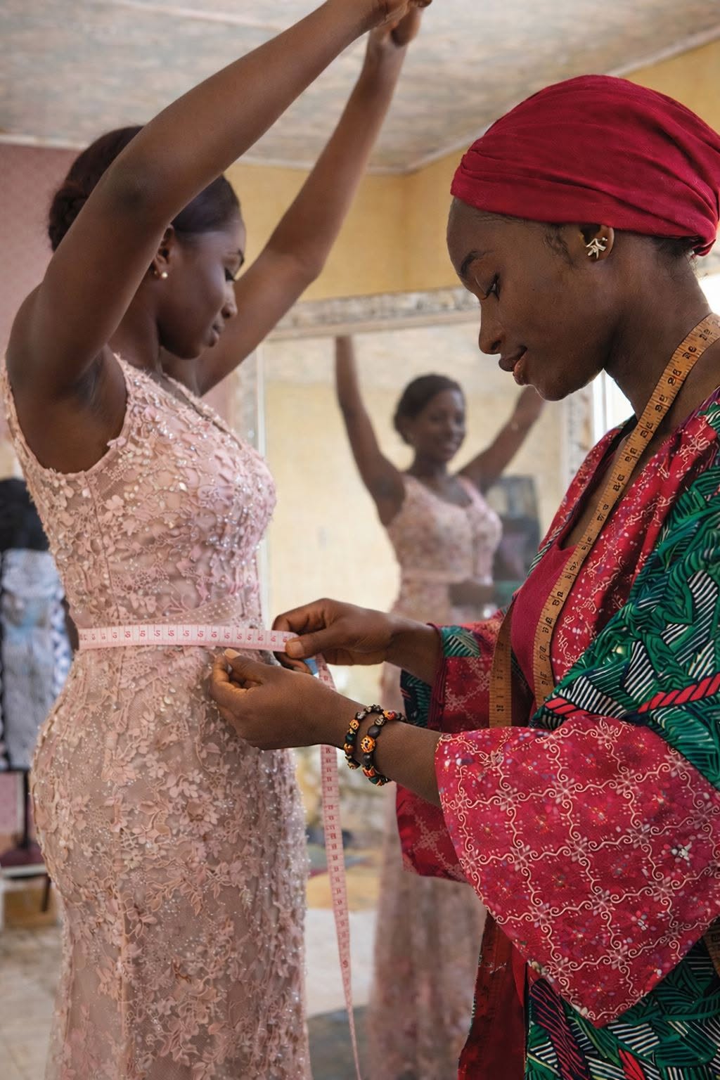 Deborah Ogbaji taking measurements on a client wearing a custom beaded pink gown